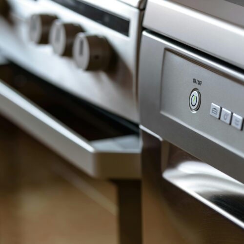 Close-up view of modern stainless steel kitchen appliances with focus on dishwasher and oven.