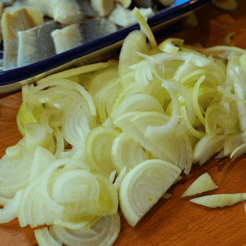 śledzie z cebulą w oleju lnianym, krojenie cebuli i czosnku